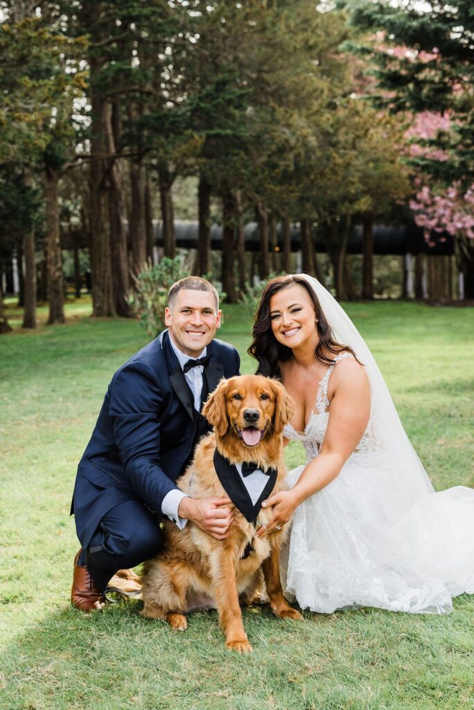 Newlyweds pose with their dog on the grounds of Flowerfield St James.